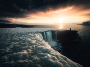 Serene Coastal Waterfall at Sunrise with Dramatic Sky and Rugged Terrain