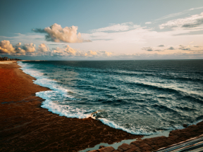 Serene Coastal Twilight: Waves Crashing on Rocky Shores Under a Colorful Sky