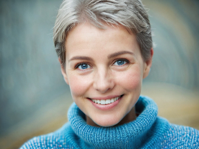Friendly Person with Short Hair Smiling Indoors in Warm Lighting