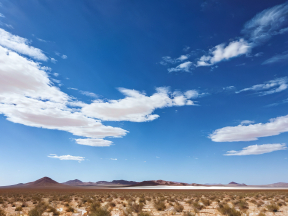 Vast Desert Landscape with Distant Hills Under a Bright Blue Sky