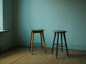 Rustic Kitchen Corner: Worn Stools and Moody Shadows on Wooden Floor