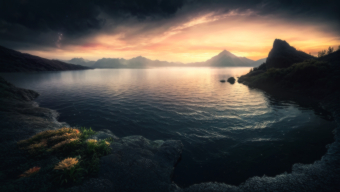Serene Mountain Lake at Sunrise: A Tranquil Landscape of Water, Rocks, and Sky