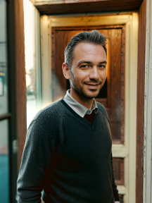 Man Smiling by Open Door in Casual Evening Setting
