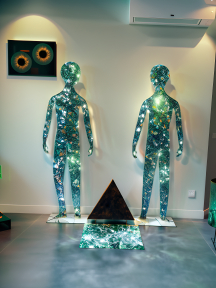 Shimmering Reflections: Life-Size Crystal Mosaic Figures Flanking a Reflective Obelisk in an Artistic Indoor Installation